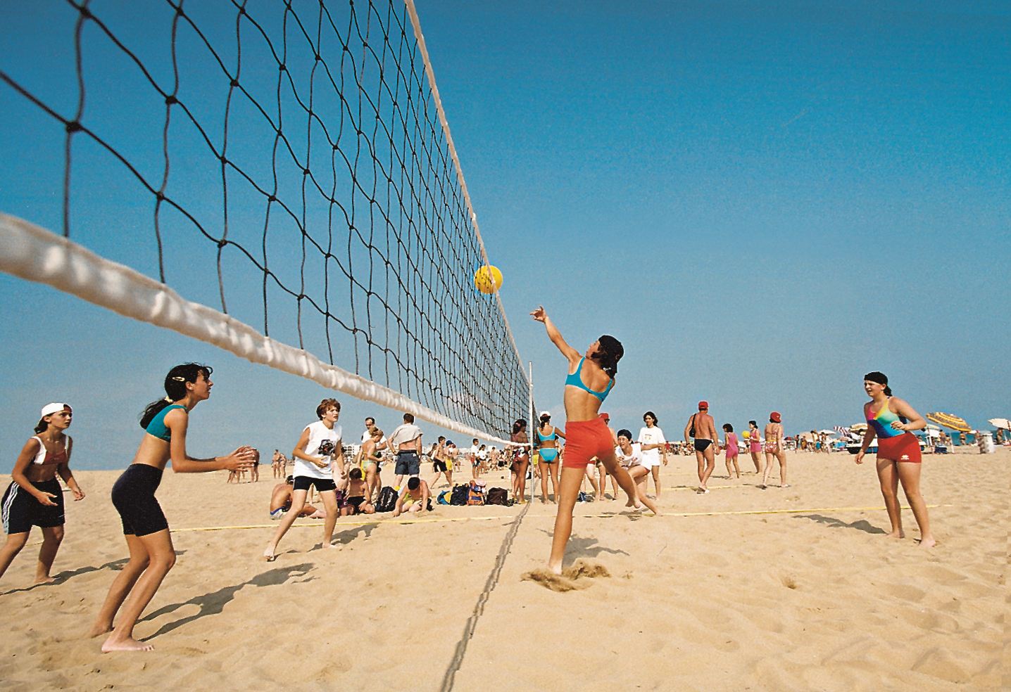 Beachvolleyball am Strand, eine Spielerin schlägt über das Netz