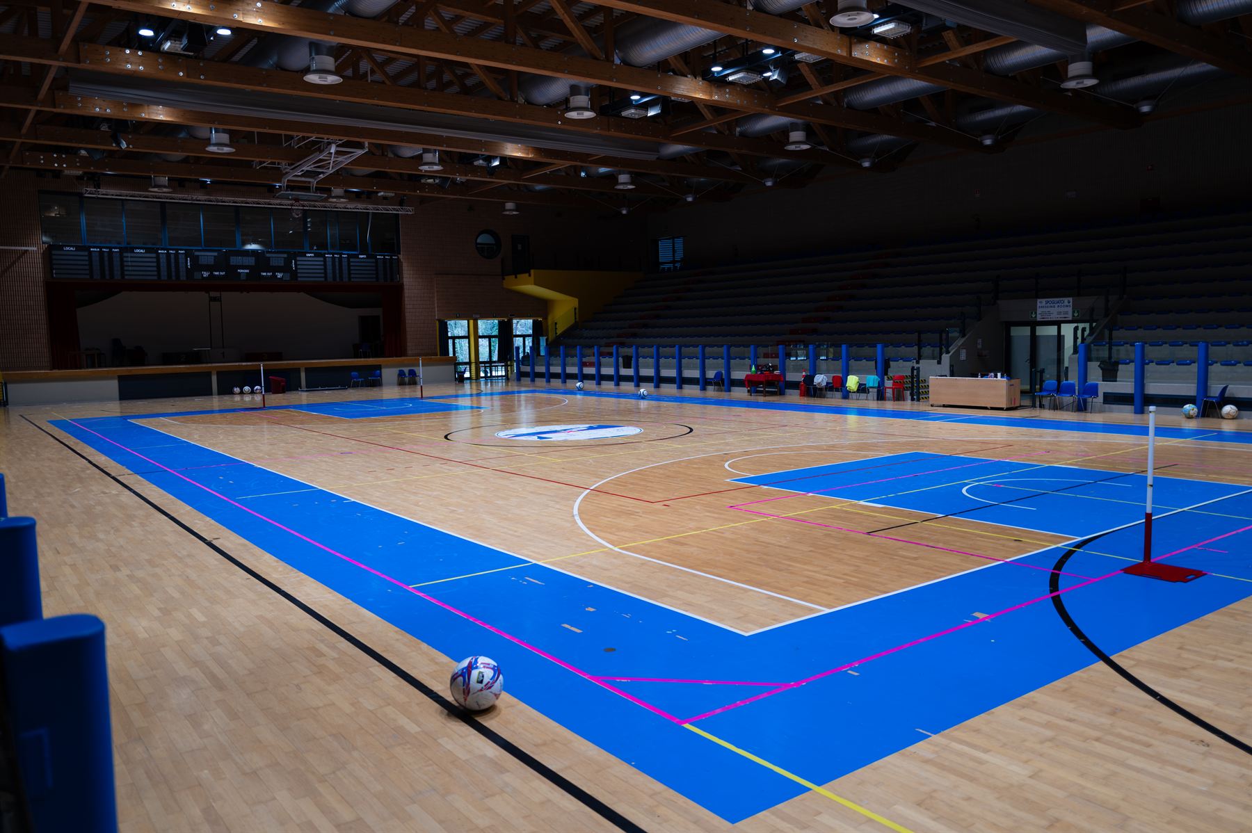 Spielfeld der Sporthalle mit Holzboden, blauen Markierungen und Tribüne