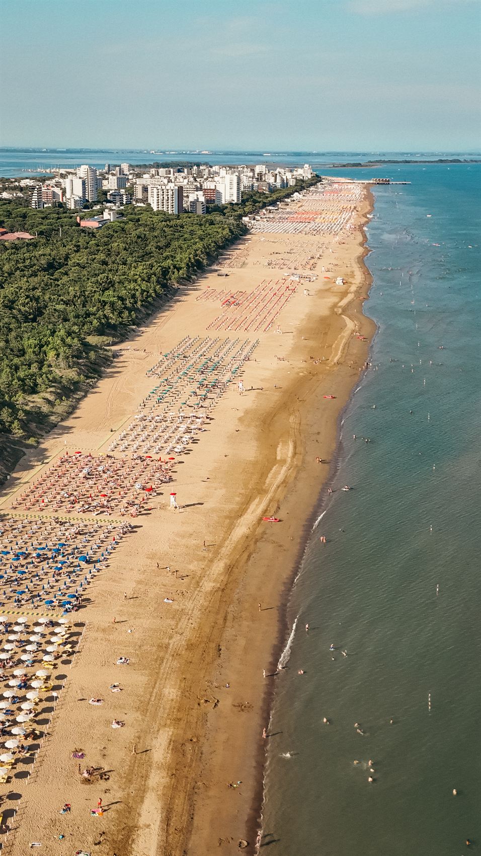 Der Sandstrand von Lignano aus der Luft, links der Pinienwald, im Hintergrund der Ort