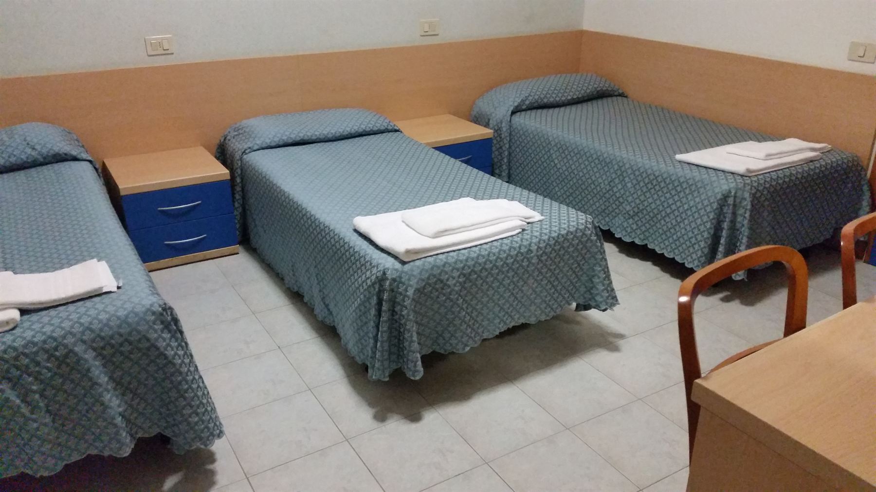 Mehrbettzimmer mit 3 Einzelbetten und Nachtkästchen